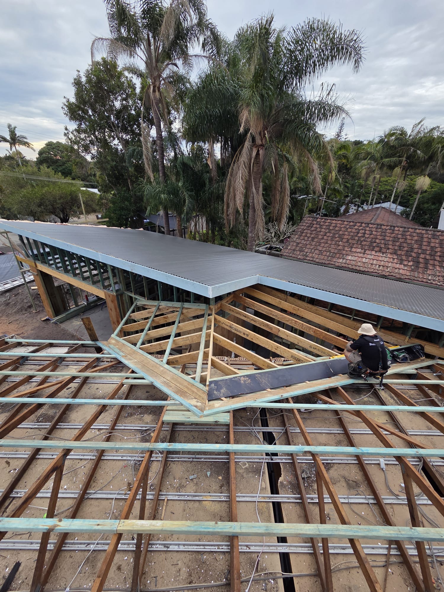 Exposed timber roof framing beside newly laid metal roofing