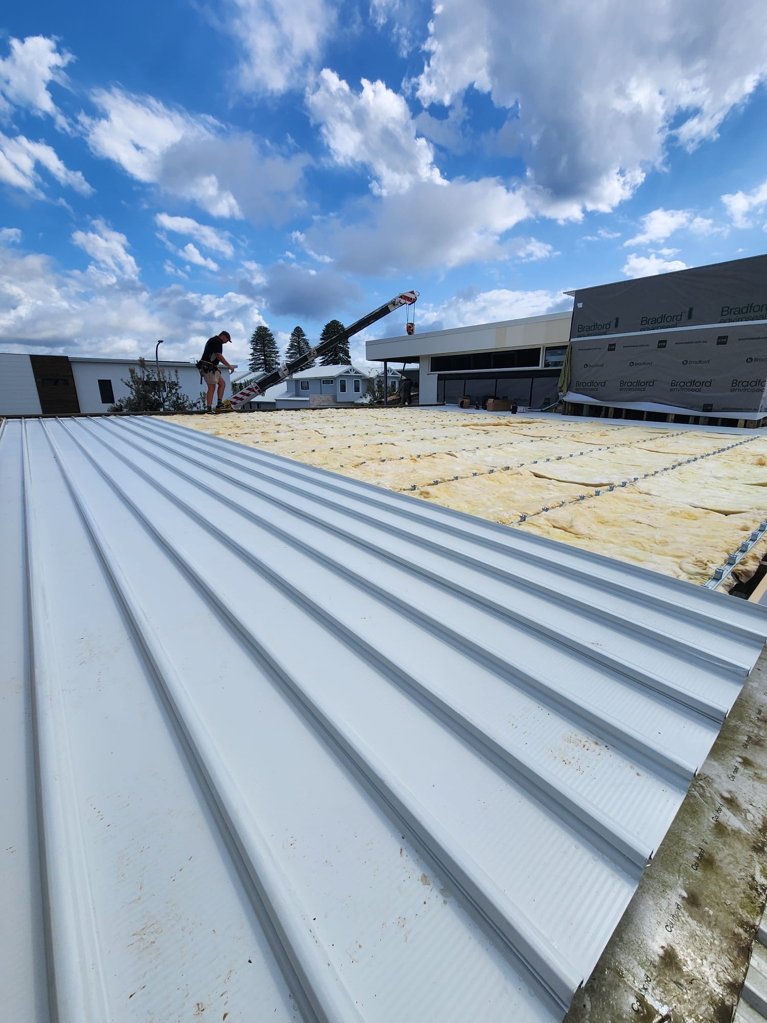 Light-coloured metal roof sheets beside insulation during installation